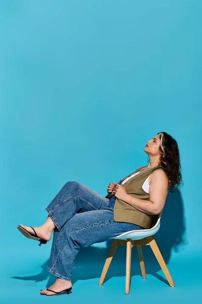 A joyful woman with Waardenburg syndrome sits in a chair against a bright blue backdrop. — Stock Photo