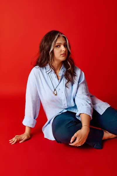 Стильная женщина с синдромом Варденбурга уверенно позирует на красном фоне.. — стоковое фото