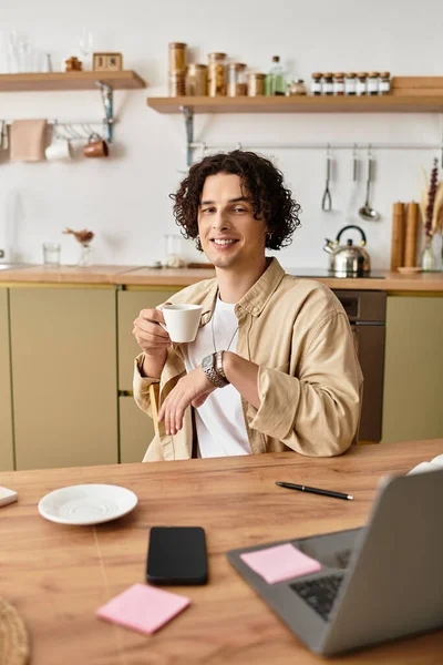 Ein gutaussehender junger Mann in Geschäftskleidung lächelt, während er in einem modernen, hellen Arbeitsbereich Kaffee schlürft. — Stockfoto