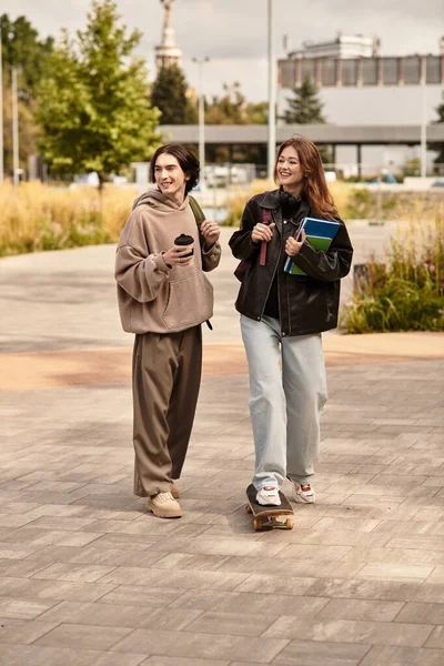 Ein Liebespaar schlendert fröhlich, das eine hält Kaffee, das andere trägt Bücher und genießt das Leben. — Stockfoto