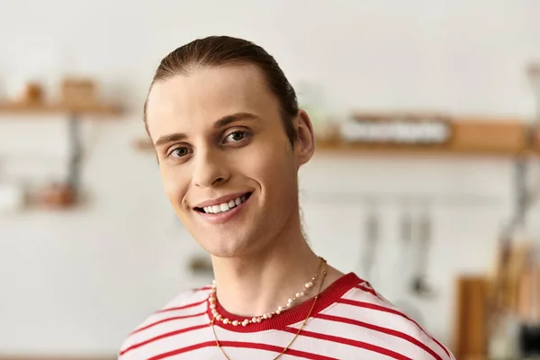 Joven con rasgos femeninos parpadea una sonrisa alegre mientras está de pie en una cocina caliente. - foto de stock