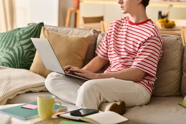Um jovem estuda em casa, imerso em seu laptop em meio a um elegante espaço de vida. — Fotografia de Stock