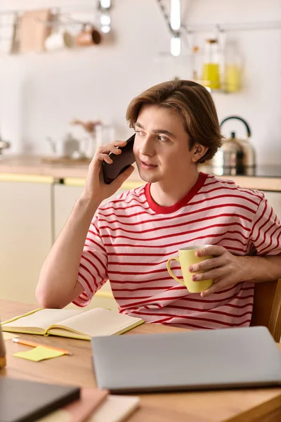 Ein junger Mann genießt eine Tasse Kaffee während seines Online-Studiums in einer gemütlichen Wohnung, die sich auf das Lernen konzentriert. — Stockfoto