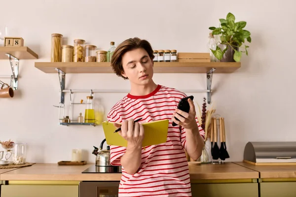 Молодой человек учится дома, сосредоточившись на ноутбуке и делая заметки в уютной квартире. — стоковое фото