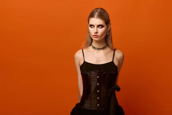 Hermosa joven posa en un llamativo disfraz de Halloween sobre un fondo naranja. - foto de stock