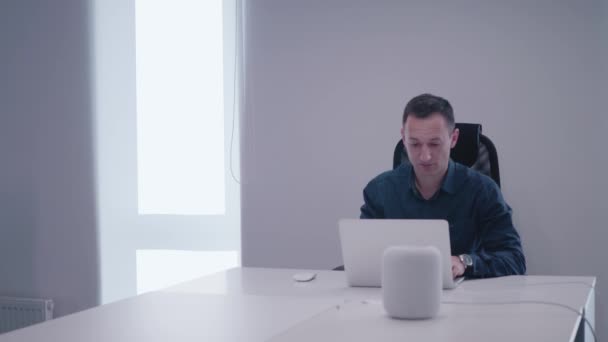 A bearded developer with tablet comes for advising to the project manager who working on laptop at the desk — Stock Video