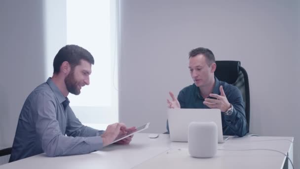 Compañeros de trabajo en la oficina animó a discutir detalles de un proyecto y uno de ellos, el desarrollador barbudo, toma notas utilizando tableta — Vídeos de Stock