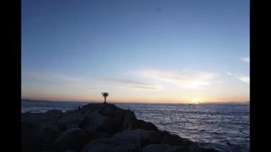 Hızlandırılmış bir deniz feneri ile sahilde günbatımı