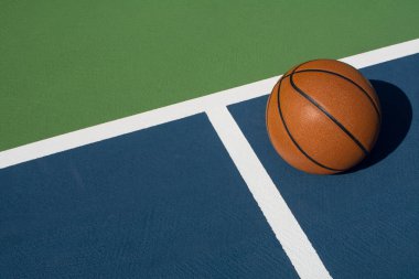 Leather basketball on colorful outdoor court - great background for your hoops related event clipart