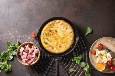 İspanyol patates omlet tortilla pastırma ile servis raf yukarıdaki malzemelerle soğutma üzerinde dökme demir tavada koyu kahverengi doku arka plan üzerinde bitti. Üstten Görünüm, uzay.