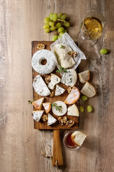 フランス産チーズのチーズ プレート品揃えウッド テクスチャ背景に蜂蜜 クルミ パンと白ワインをグラスで素朴な木製サービング ボードのブドウを添えてください スペース平面図 — ストック写真