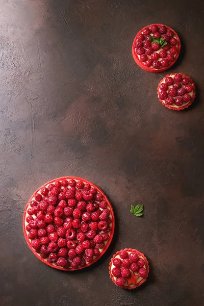 各种红莓酥挞和 Tartlets 柠檬奶油和釉上新鲜的覆盆子在深褐色的纹理背景 顶部视图 — 图库照片