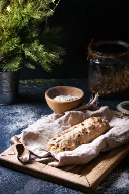 Christmas cake, geleneksel Alman şenlikli pişirme. Kepekli hamur stollen hazırlık ile keten peçete üzerinde koyu mavi doku arka plan üzerinde un, Kuru üzüm, köknar ağacı kase. Rustik tarzı