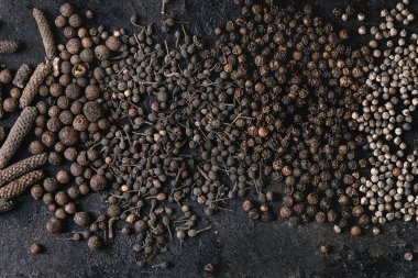 Çeşitli farklı siyah biber yenibahar, yenibahar, uzun biber, rahipler biber, karabiber eski siyah demir doku yüzey üzerinde. Gıda arka plan. Üstten görünüm, uzay.