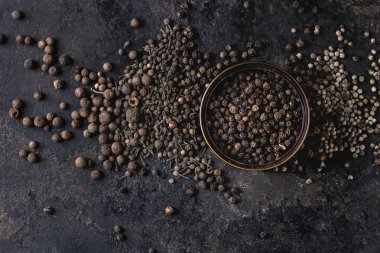 Farklı siyah biber yenibahar, yenibahar, rahipler biber, karabiber ve zemin toz eski siyah demir doku arka plan üzerinde teneke kutu içinde çeşididir. Üstten görünüm, uzay.