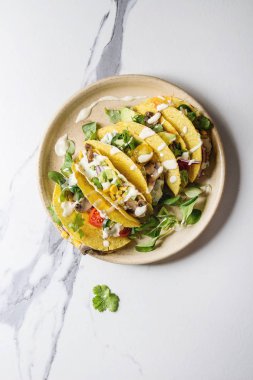 Çeşitli vejetaryen Mısır Tacos sebze, yeşil salata, biber ile krema sosu ile seramik plaka üzerinde beyaz mermer arka plan üzerinde servis. Üstten görünüm, kopya alanı.