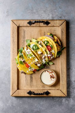 Çeşitli vejetaryen Mısır Tacos sebze, yeşil salata, biber ile krema sosu ile ahşap tepsi üzerinde gri doku arka plan üzerinde servis. Üstten görünüm, uzay.