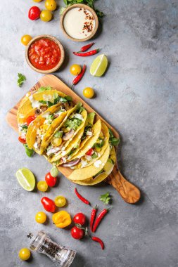 Çeşitli vejetaryen Mısır Tacos sebze, yeşil salata, biber biber domates ile zeytin ahşap masa, malzemelerle krem soslar üzerinde gri doku arka plan üzerinde servis. Üstten görünüm, uzay.