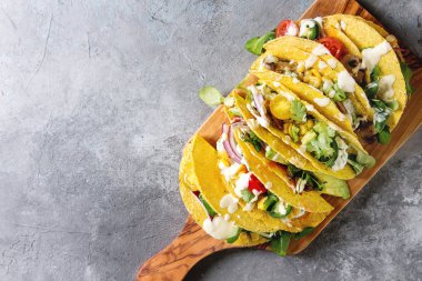 Çeşitli vejetaryen Mısır Tacos sebze, yeşil salata, biber ile krema sosu ile zeytin ahşap tahta üzerinde gri doku arka plan üzerinde servis. Üstten görünüm, kopya alanı.