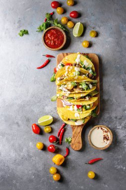 Çeşitli vejetaryen Mısır Tacos sebze, yeşil salata, biber biber domates ile zeytin ahşap masa, malzemelerle krem soslar üzerinde gri doku arka plan üzerinde servis. Üstten görünüm, uzay.