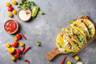 Çeşitli vejetaryen Mısır Tacos sebze, yeşil salata, biber biber domates ile zeytin ahşap masa, malzemelerle krem soslar üzerinde gri doku arka plan üzerinde servis. Üstten görünüm, uzay.