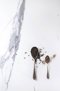 Kara biber peppercorns ve zemin toz beyaz üzerinde vintage kaşık içinde doku arka plan mermer. Üstten görünüm, uzay.