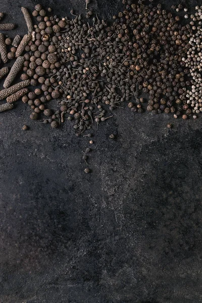 さまざまな異なるブラック ピーマン オール スパイス ピメント ロングペッパー 修道士のコショウを古い黒鉄テクスチャ表面に胡椒 食品の背景 スペース平面図 — ストック写真