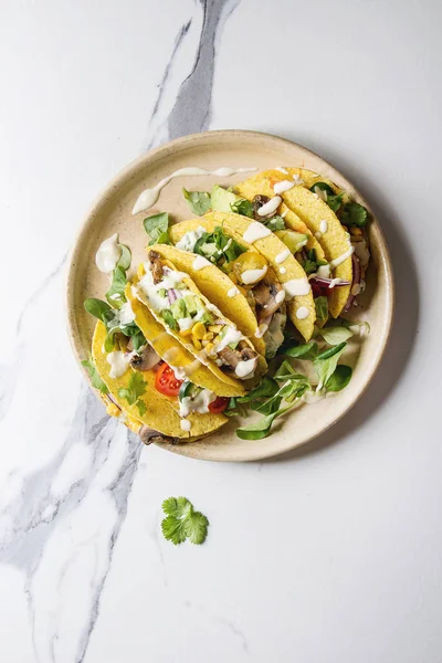 Çeşitli vejetaryen Mısır Tacos sebze, yeşil salata, biber ile krema sosu ile seramik plaka üzerinde beyaz mermer arka plan üzerinde servis. Üstten görünüm, kopya alanı.