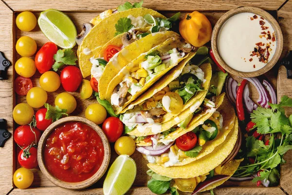 Çeşitli vejetaryen Mısır Tacos sebze, yeşil salata, biber biber domates ile ahşap tepsi ve yukarıdaki malzemelerle krem soslar servis. Görünümü en çok, yakın çekim.