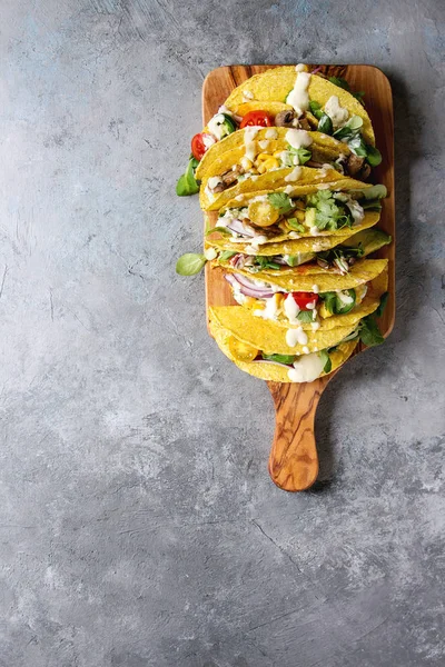 Çeşitli vejetaryen Mısır Tacos sebze, yeşil salata, biber ile krema sosu ile zeytin ahşap tahta üzerinde gri doku arka plan üzerinde servis. Üstten görünüm, kopya alanı.