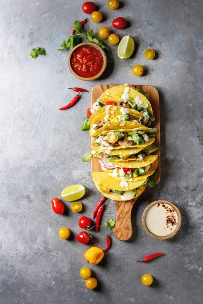 Çeşitli vejetaryen Mısır Tacos sebze, yeşil salata, biber biber domates ile zeytin ahşap masa, malzemelerle krem soslar üzerinde gri doku arka plan üzerinde servis. Üstten görünüm, uzay.