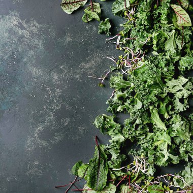 Salata için yeşil salata karışımı veya kale ile güler yüzlü, genç pancar yaprakları, lahanası, karanlık doku yüzey üzerinde. Üstten Görünüm alanı. Gıda arka plan.