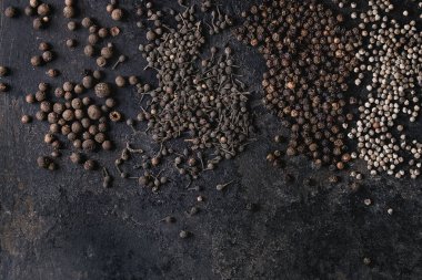 Farklı siyah biber yenibahar, yenibahar, rahipler biber, karabiber eski siyah demir doku yüzey üzerinde çeşitli. Gıda arka plan. Üstten görünüm, uzay.
