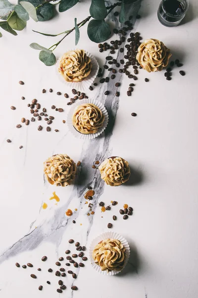 新鲜烘焙自制的蛋糕与咖啡奶油和焦糖与桉树分支和咖啡豆以上的白色大理石背景 — 图库照片