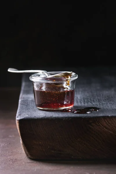 自制液体透明红糖焦糖在玻璃罐子站立在黑木板用勺子 — 图库照片