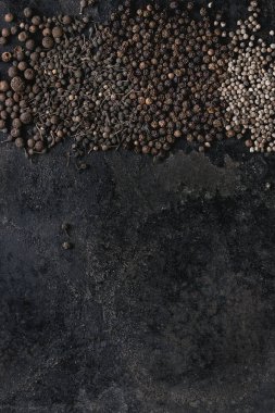 Farklı siyah biber yenibahar, yenibahar, rahipler biber, karabiber eski siyah demir doku yüzey üzerinde çeşitli. Gıda arka plan. Üstten görünüm, uzay.