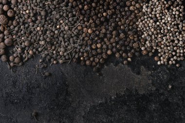 Farklı siyah biber yenibahar, yenibahar, rahipler biber, karabiber eski siyah demir doku yüzey üzerinde çeşitli. Gıda arka plan. Üstten görünüm, uzay.