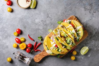 Çeşitli vejetaryen Mısır Tacos sebze, yeşil salata, biber biber domates ile zeytin ahşap masa, malzemelerle krem soslar üzerinde gri doku arka plan üzerinde servis. Üstten görünüm, uzay.