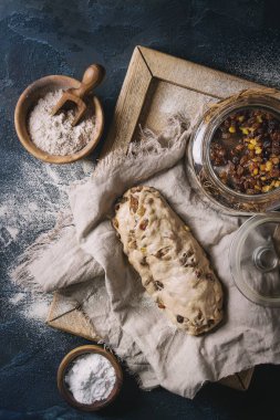 Christmas cake, geleneksel Alman şenlikli pişirme. Kepekli hamur stollen hazırlık ile keten peçete üzerine un ve kuru üzüm koyu mavi doku arka plan üzerinde kase. Üstten görünüm, uzay