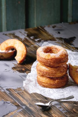 Ev yapımı puf böreği derin kızarmış çörek veya cronuts şeker buruşuk ayakta yığınındaki koyu ahşap beton masa üzerinde kağıt.