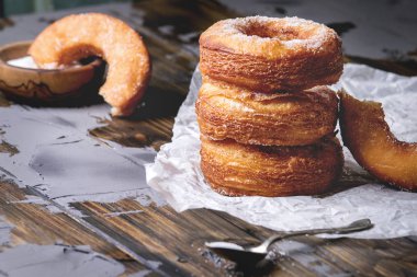 Ev yapımı puf böreği derin kızarmış çörek veya cronuts şeker buruşuk ayakta yığınındaki koyu ahşap beton masa üzerinde kağıt.