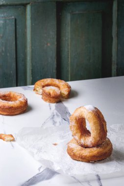 Ev yapımı puf böreği derin kızarmış çörek veya cronuts şeker buruşuk ayakta beyaz mermer mutfak masasının üzerinde kağıt.