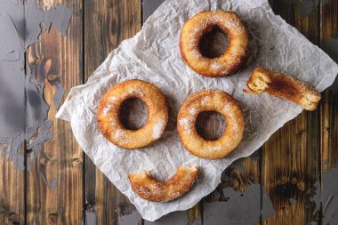 Ev yapımı puf böreği derin kızarmış çörek veya cronuts şeker buruşuk ayakta yığınındaki koyu ahşap beton doku arka plan üzerinde kağıt. Düz lay, uzay.