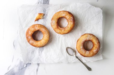 Ev yapımı puf böreği derin kızarmış çörek veya cronuts beyaz mermer doku arka plan üzerinde buruşuk Kağıt üzerinde şekerli. Düz lay, uzay.