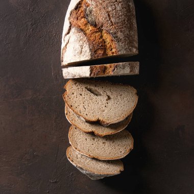 Taze pişmiş esnaf somun koyu kahverengi doku arka plan üzerinde siyah ekmek dilimlenmiş. Görünümü en çok, uzay kopyalayın. Kare görüntü