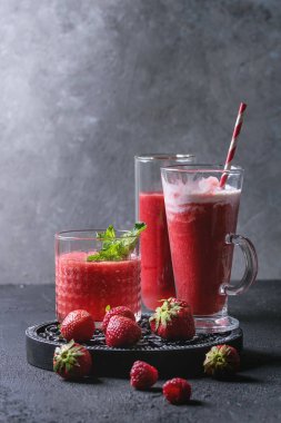 Üç farklı kırmızı meyve karpuz, çilek, ahududu, nar kokteyl veya ezilmiş buz, nane ve siyah doku tablo yukarıda malzemeler ile bardaklarda smoothies berry. Gıda natürmort.