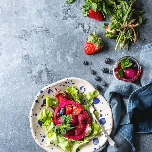 Vegan meyve salatası çilek ve nane ile mavi doku arka plan üzerinde pembe dragon meyve bezle seramik plaka üzerinde malzemelerle görev yaptı. Üstten Görünüm alanı. Sağlıklı beslenme