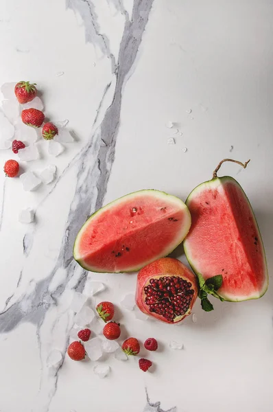 Kırmızı olgun organik meyve çeşitli meyve karpuz, çilek, ahududu, nar kokteyl veya nane ile smoothies ve beyaz mermer arka plan üzerinde buz ezilmiş. Düz yatıyordu