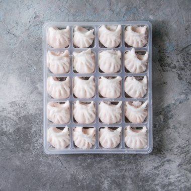 Gri doku arka plan üzerinde karides plastik kutu tarafından doldurulmuş Asya potstickers köfte yemek için hazır dondurulmuş. Üstten görünüm alanı. Stoklar ürün. Kare görüntü