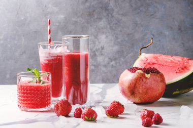 Üç farklı kırmızı meyve karpuz, çilek, ahududu, nar kokteyl veya ezilmiş buz, taze nane ve beyaz mermer tablo yukarıda malzemeler bardaklarda smoothies berry.